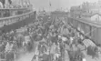 Black and white image of vendors on a dock next to a ship.