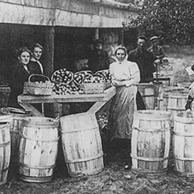 Black and white image of women around barrels.