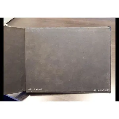 A closed black photo album labeled 4B Clinkman and 2016.067.001 rests on a wooden surface with its cover slightly open.